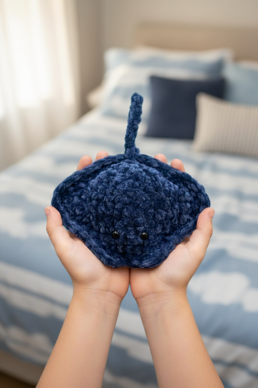 Mini raie Manta crochet bleu marine tenue par un enfant dans une chambre cosy bleue et blanche